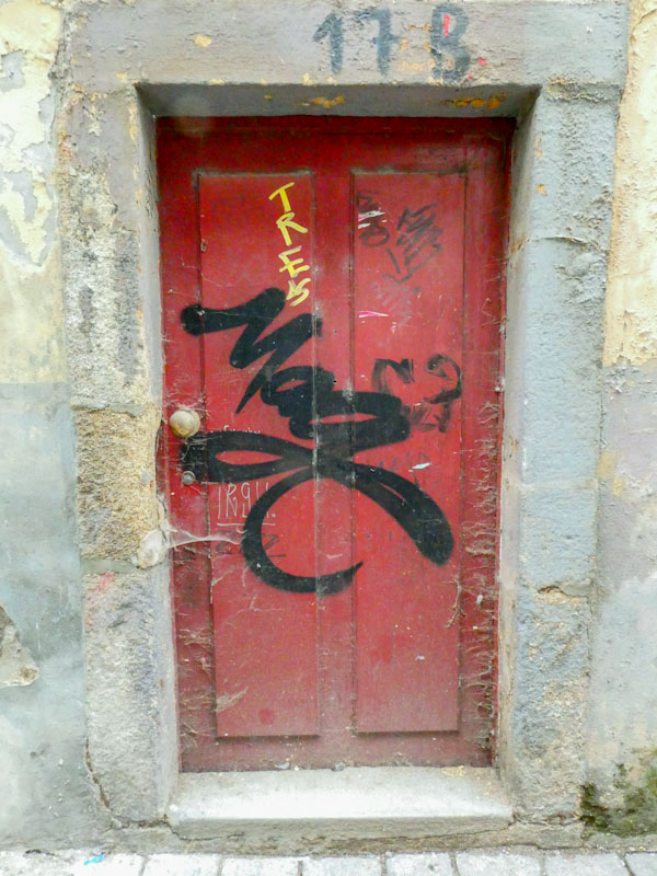 Red door with a large tag (Mage?), Porto, Portugal, June 2023