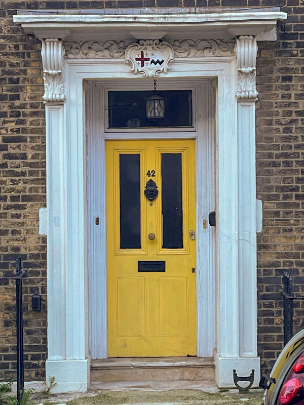 Yellow door with fancy crest, Highgate, London, November 2023
