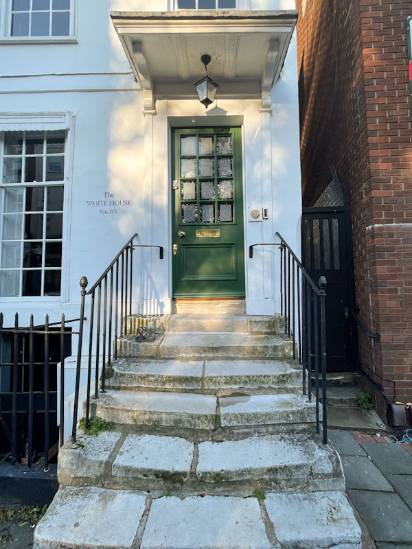 Green door with large flat awning and worn steps, Highgate, London, November 2023